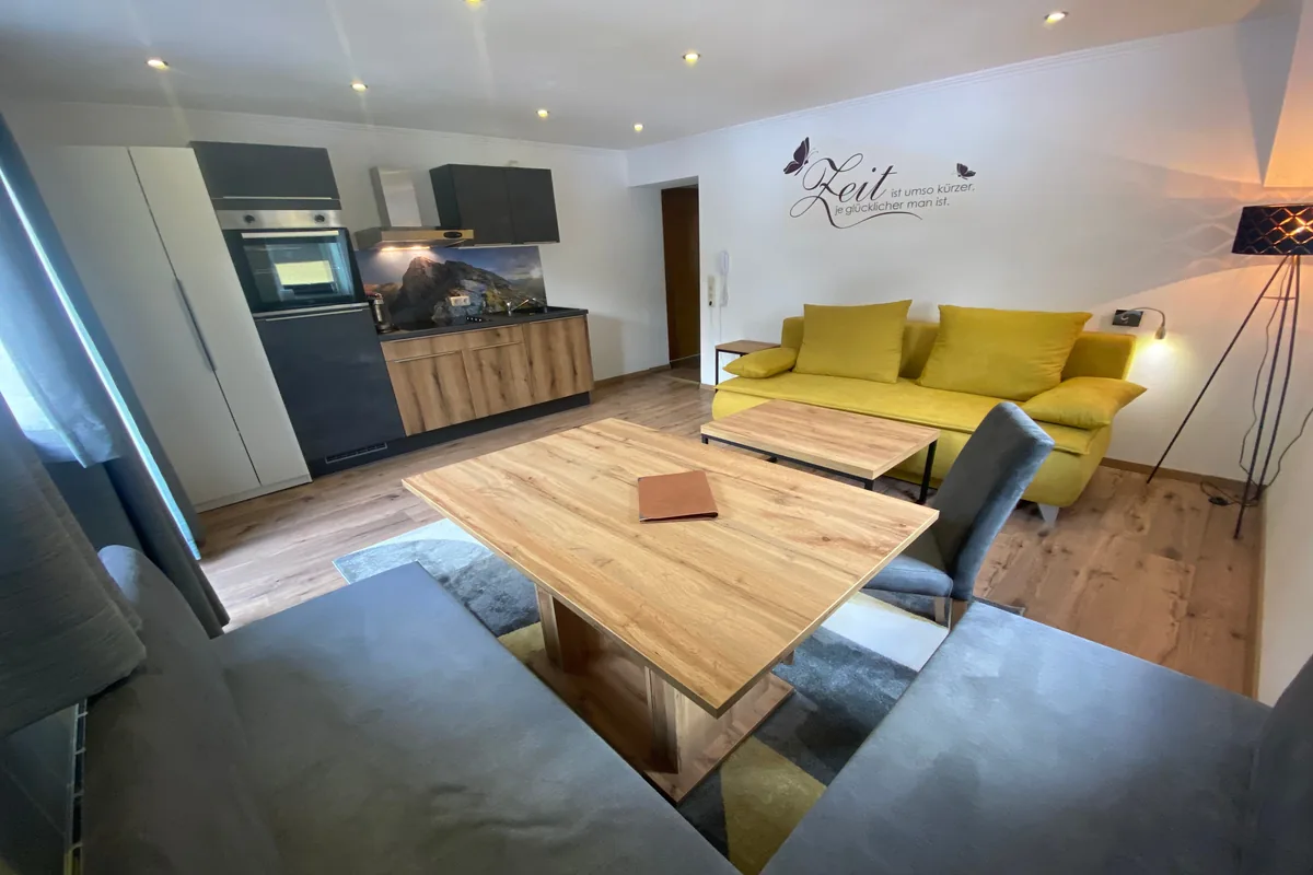 Wohnbereich im Apartment Großglockner mit Boxspring-Schlafsofa und voll ausgestatteter Küche bei GRUBERS Hotel-Apartments Gastein