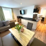 Apartment Kreukogel Bad Gastein Wohnbereich mit Essbank und Blick vom Wohnbereich ins Schlafzimmer mit Hund